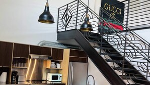 Een moderne keuken met een centraal eiland, roestvrijstalen apparatuur en een trap met een metalen leuning.