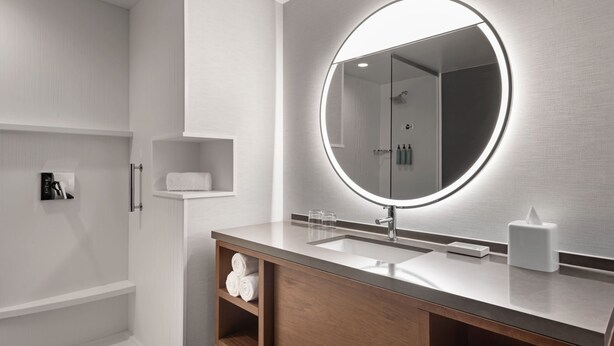 A modern bathroom with a large mirror, a sink, and a shower area. - Courtyard by Marriott Marina del Rey (Marina del Rey)