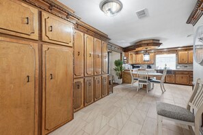 A spacious kitchen with wooden cabinetry, a dining area with a table and chairs, and a large island. - Prestige Mountain View with a relaxing Waterfront at Arkansas River. (Howard)