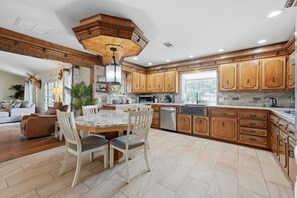 A spacious kitchen with wooden cabinets, a granite countertop, and a dining area with a table and chairs. - Prestige Mountain View with a relaxing Waterfront at Arkansas River. (Howard)