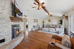 A spacious living room with a fireplace, a large ceiling fan, and a mounted deer head. - Prestige Mountain View with a relaxing Waterfront at Arkansas River. (Howard)