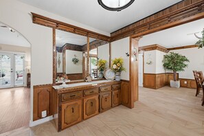 Een badkamer met houten kastjes, een grote spiegel en een potplant.
