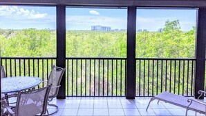 A balcony with a table and chairs, a view of greenery and buildings in the distance. - Paradise in Naples (Naples)