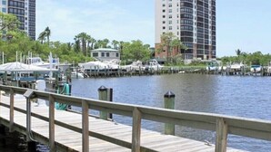 A waterfront view with a wooden dock, boats, and high-rise buildings in the background. - Paradise in Naples (Naples)