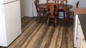 Une cuisine équipée d’un réfrigérateur, d’une table à manger en bois et de chaises.