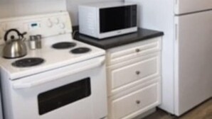 Une cuisine avec des armoires blanches, une cuisinière blanche, un four à micro-ondes et un réfrigérateur.