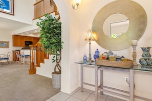 Staircase leads to an upper level, with a dining area and glass console table below.