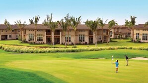 A golf course with a clubhouse and palm trees. - Luxury Villa • AC • Golf Views • Walk to Pool, Beach & Shop (Waikoloa)