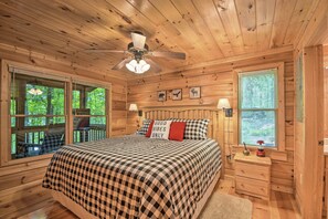 A wooden cabin bedroom with a bed, two windows, a ceiling fan, and a nightstand. - 'Pinot & Pine' Chic Log Cabin ~ 5 Mi to Blue Ridge (Blue Ridge)