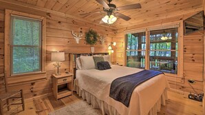 A wooden cabin bedroom with a bed, nightstands, a ceiling fan, and a window with blinds. - 'Pinot & Pine' Chic Log Cabin ~ 5 Mi to Blue Ridge (Blue Ridge)