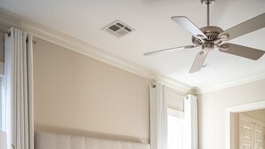 A bedroom with a large bed, a nightstand, a ceiling fan, and a window with curtains. - Explore Magazine Street from a Chic, Tranquil Home (New Orleans)