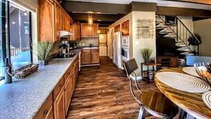 Eine moderne Küche mit Holzausbau, einer Arbeitsplatte aus Granit und einem Essbereich mit Holztisch und -stühlen.