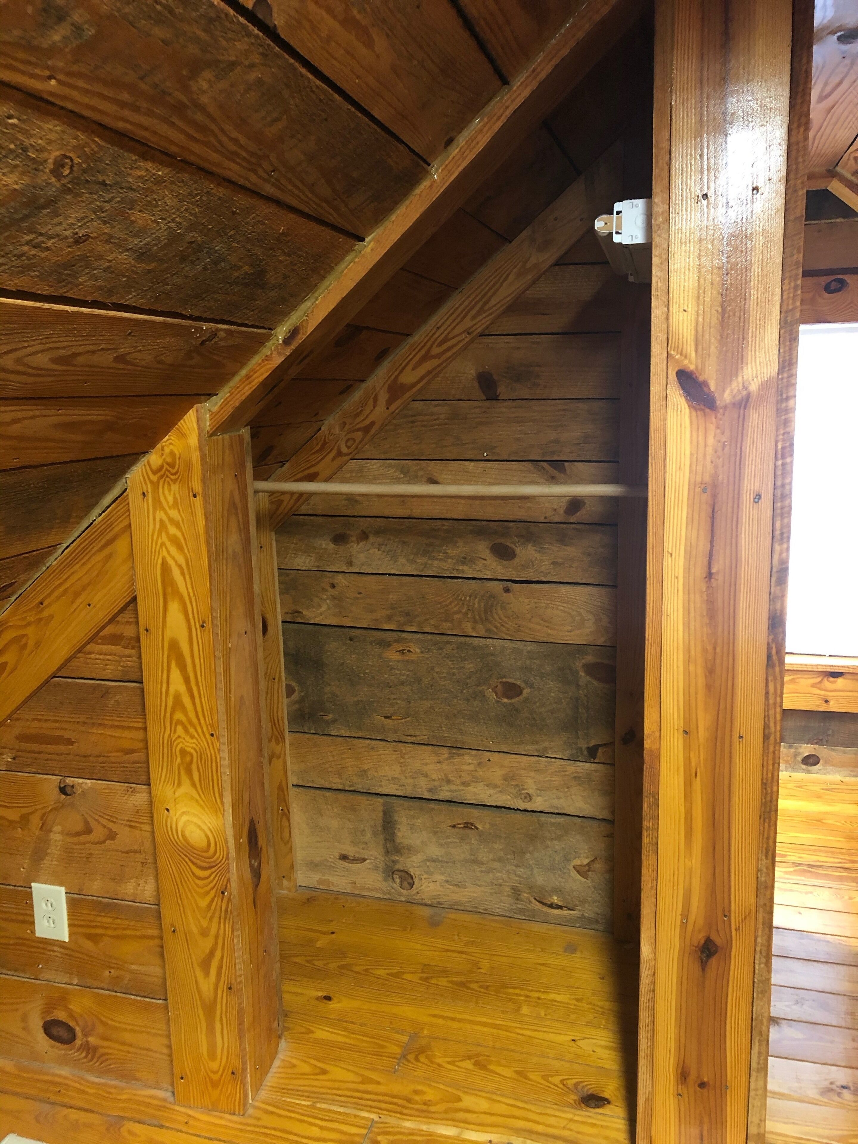 Un escalier en bois avec une rampe en bois et une prise électrique blanche fixée au mur.