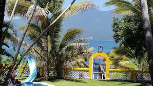 A pool area with a slide, palm trees, and a view of the ocean.