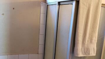 A small bathroom with a toilet, a shower enclosure, and a window above the toilet.
