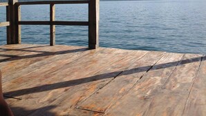 A wooden deck with a metal roof overlooking a calm lake and distant mountains.