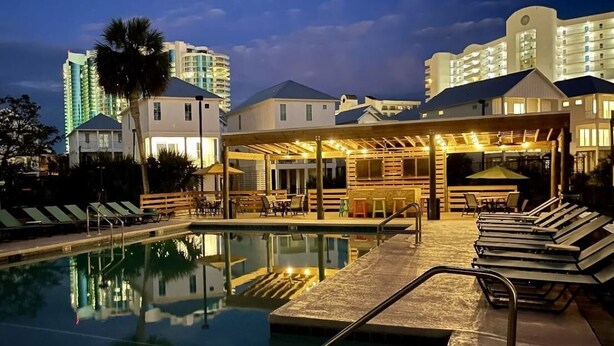 A hotel pool area with lounge chairs, a bar, and a covered seating area. - Spacious condo across beach access! Bring your boat! Dock slips, pool & more! (Orange Beach)