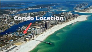 An aerial view of a coastal area with a marked condo location indicated by a red arrow. - Spacious condo across beach access! Bring your boat! Dock slips, pool & more! (Orange Beach)