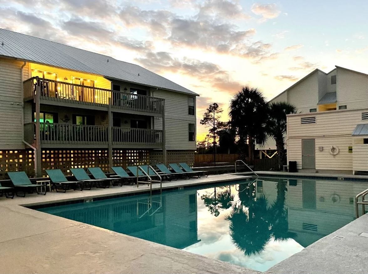 Una piscina con sillones de descanso y un edificio con balcones.