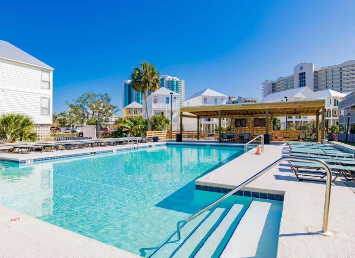 A swimming pool with lounge chairs and a covered seating area.