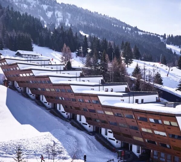 A modern hotel with a unique architectural design, featuring a series of interconnected rooms with large windows and a sloped roof.
