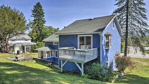 Une maison à deux étages, à l’extérieur bleu, dotée d’un porche et de fondations en pierre.