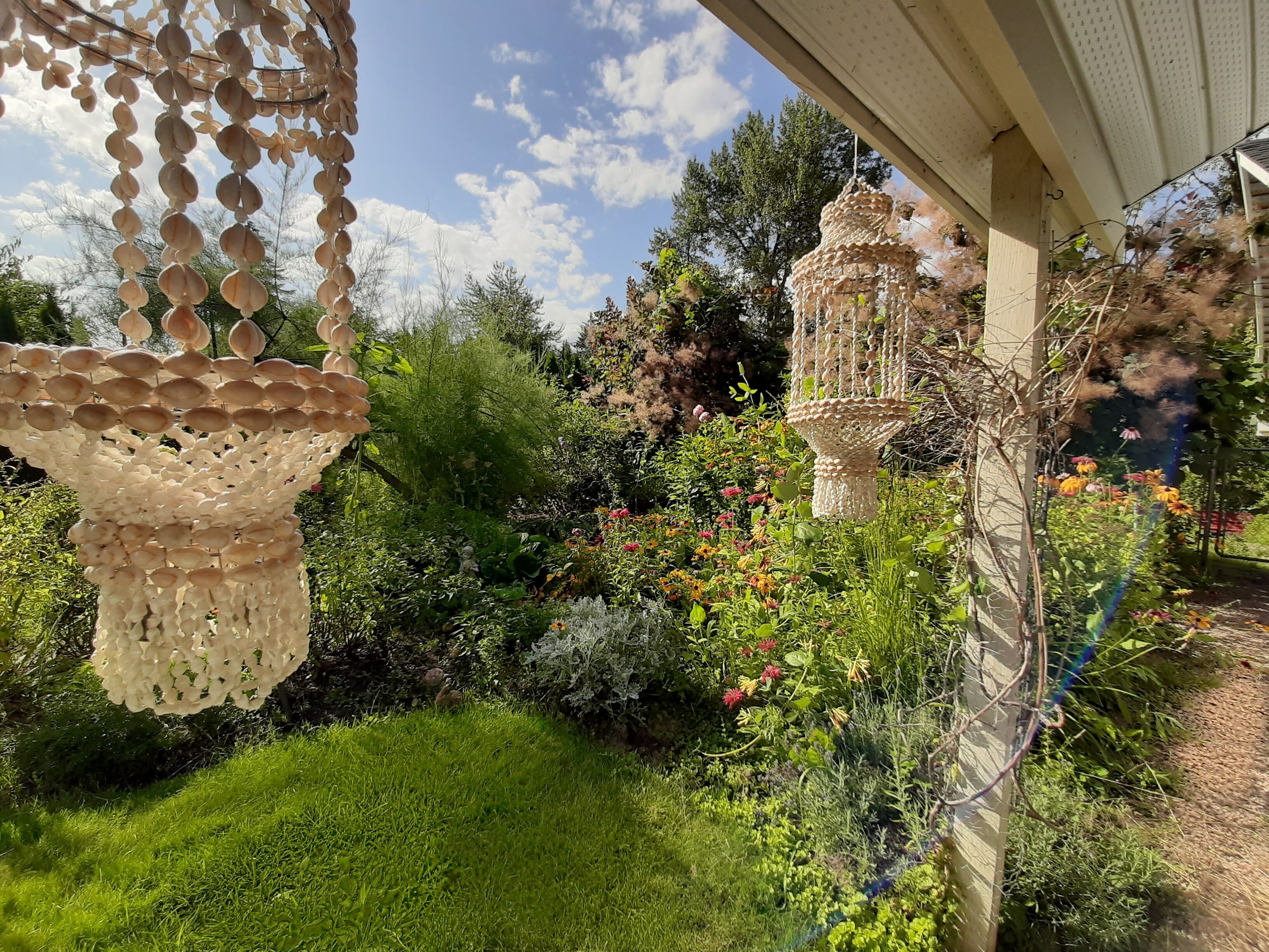 A garden with hanging decorative structures and a variety of plants and flowers.