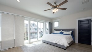 A bedroom with a bed, a ceiling fan, and a view through large windows. - Just redone, 1 1/2 block from Ventnor beach (Ventnor City)