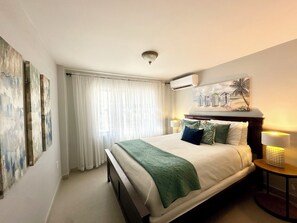 Un dormitorio con cama, cortinas, aire acondicionado instalado en la pared y un cuadro.