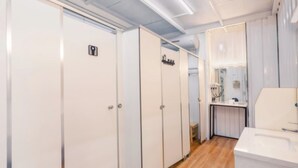 Un baño de hotel con taquillas blancas, un lavabo y un espejo.