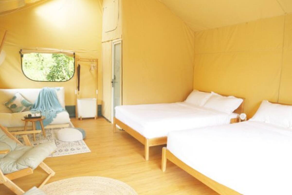 Une chambre confortable aménagée comme une tente, avec deux lits, un canapé et une petite table.