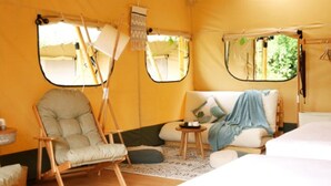 Una habitación tipo tienda de campaña acogedora, con una cama, una mecedora y una pequeña mesa.