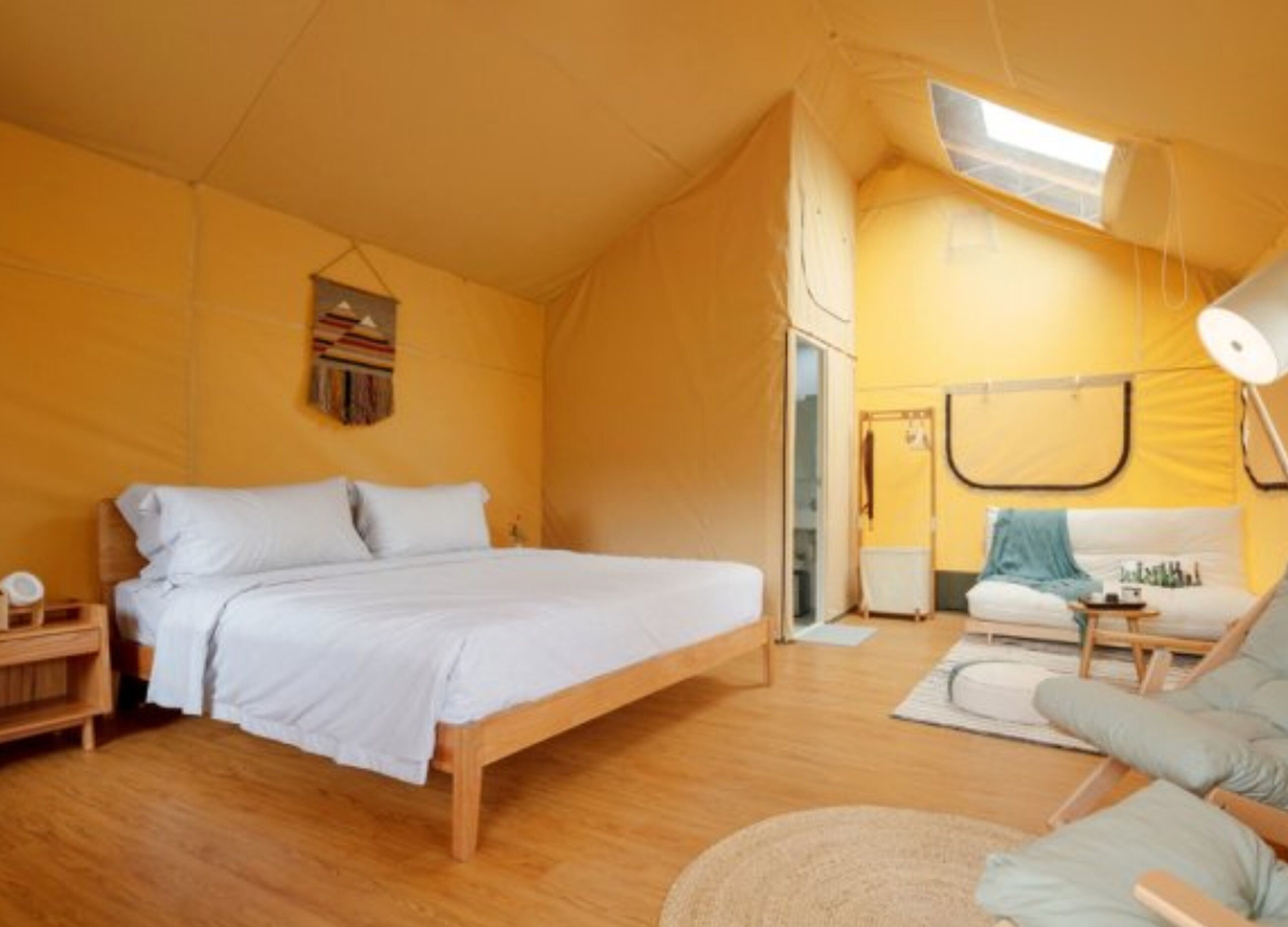 Una habitación acogedora con una cama, una mesita, una silla y un sofá.