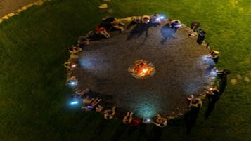 A circular arrangement of people around a central fire, possibly for a gathering or event.