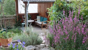 Un jardín con terraza de madera, una mesa y sillas.