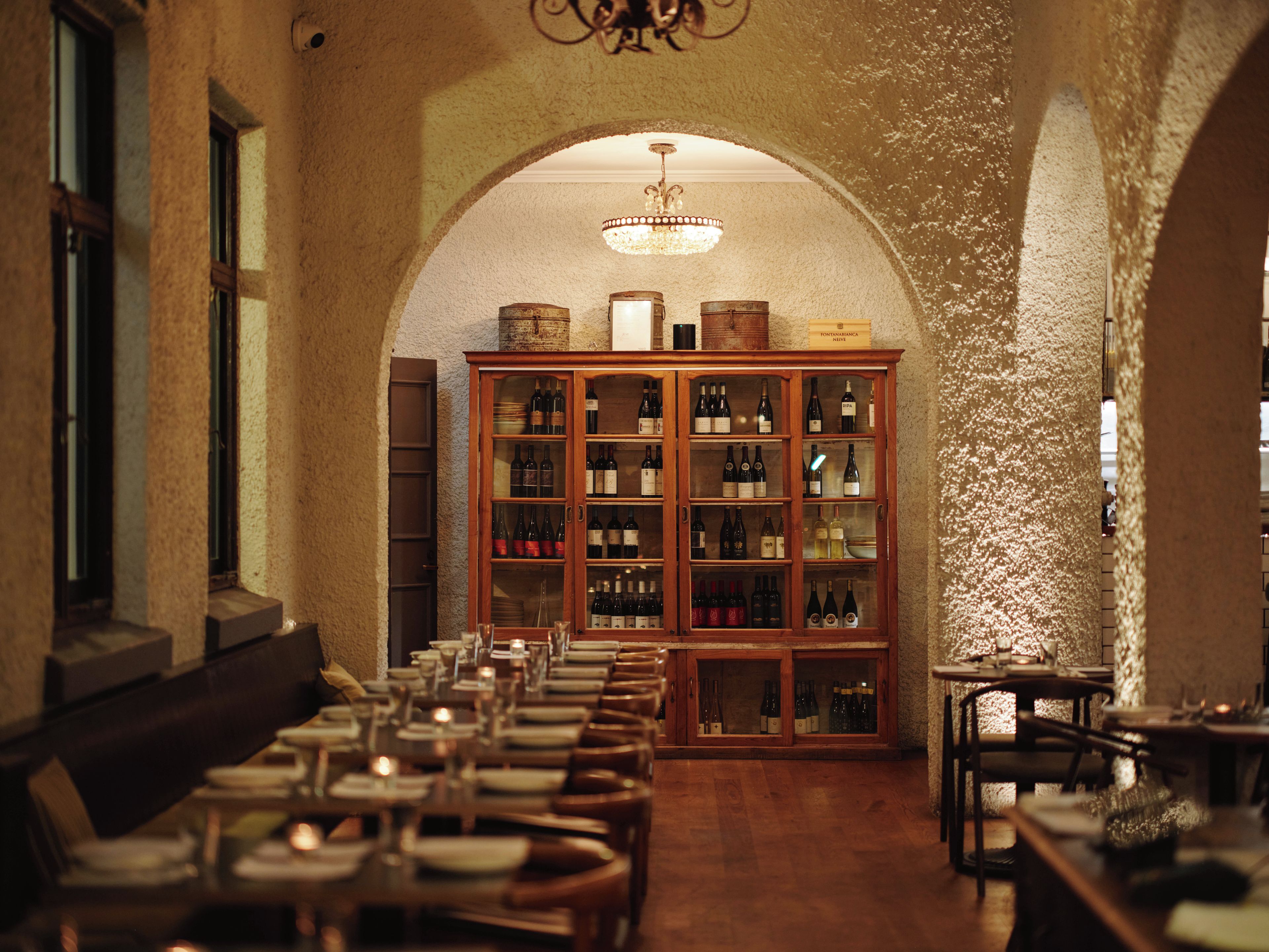 Ein Restaurant mit einem langen Esstisch, einer Weinschlappe und einem Kronleuchter.
