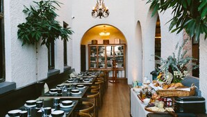 Un restaurante con mesas largas, sillas y una variedad de comidas y bebidas en una mesa de buffet.