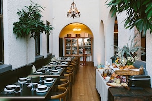 A restaurant with long tables, chairs, and a variety of food and drink items on a buffet table.