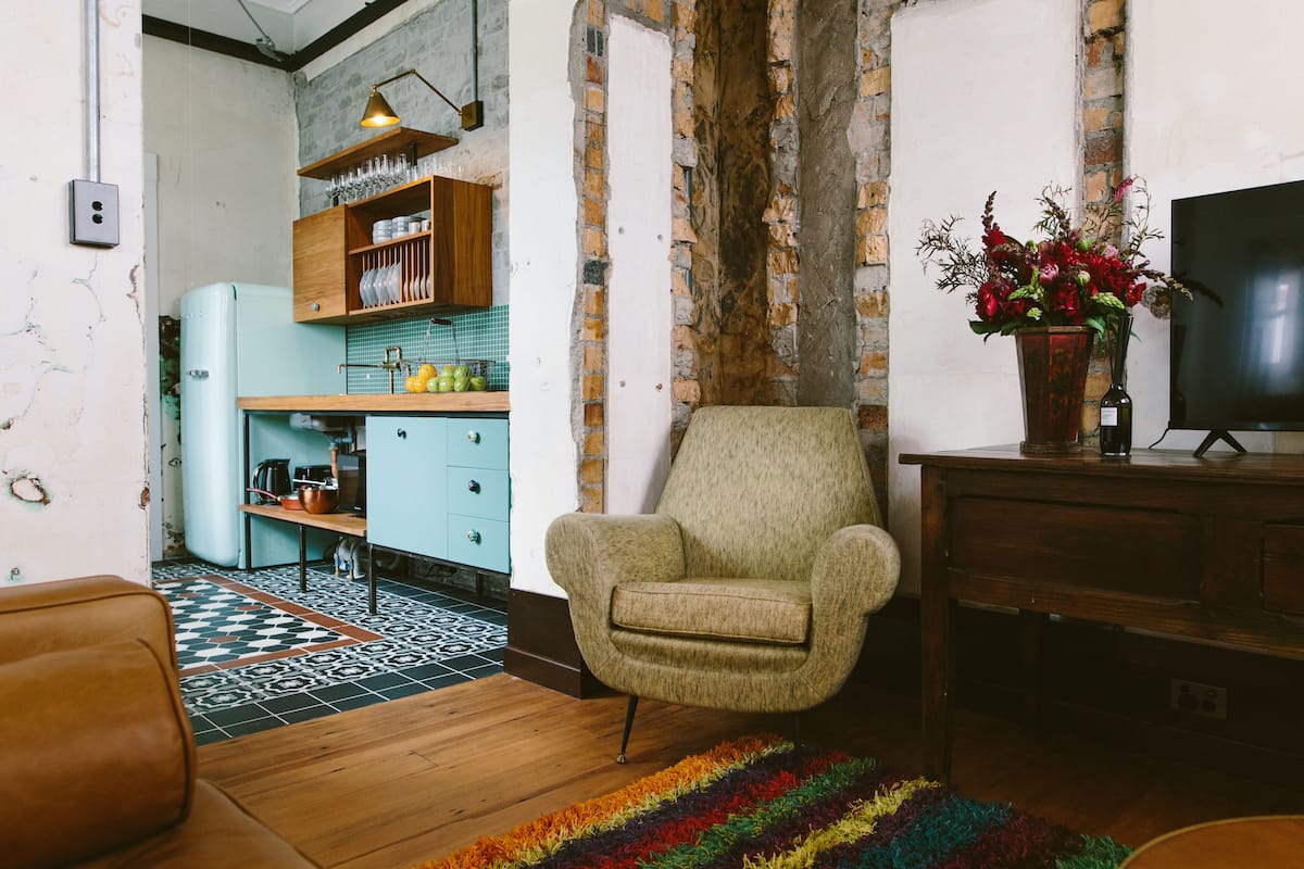 A living room with a vintage armchair, a television, and a colorful rug.