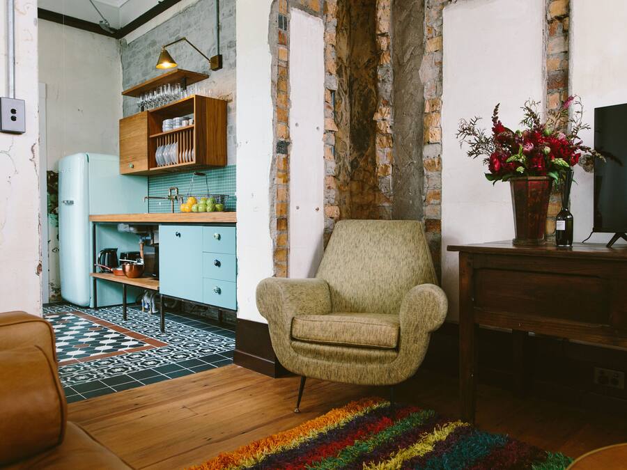 Una sala de estar con un sillón antiguo, un televisor y un tapete colorido.