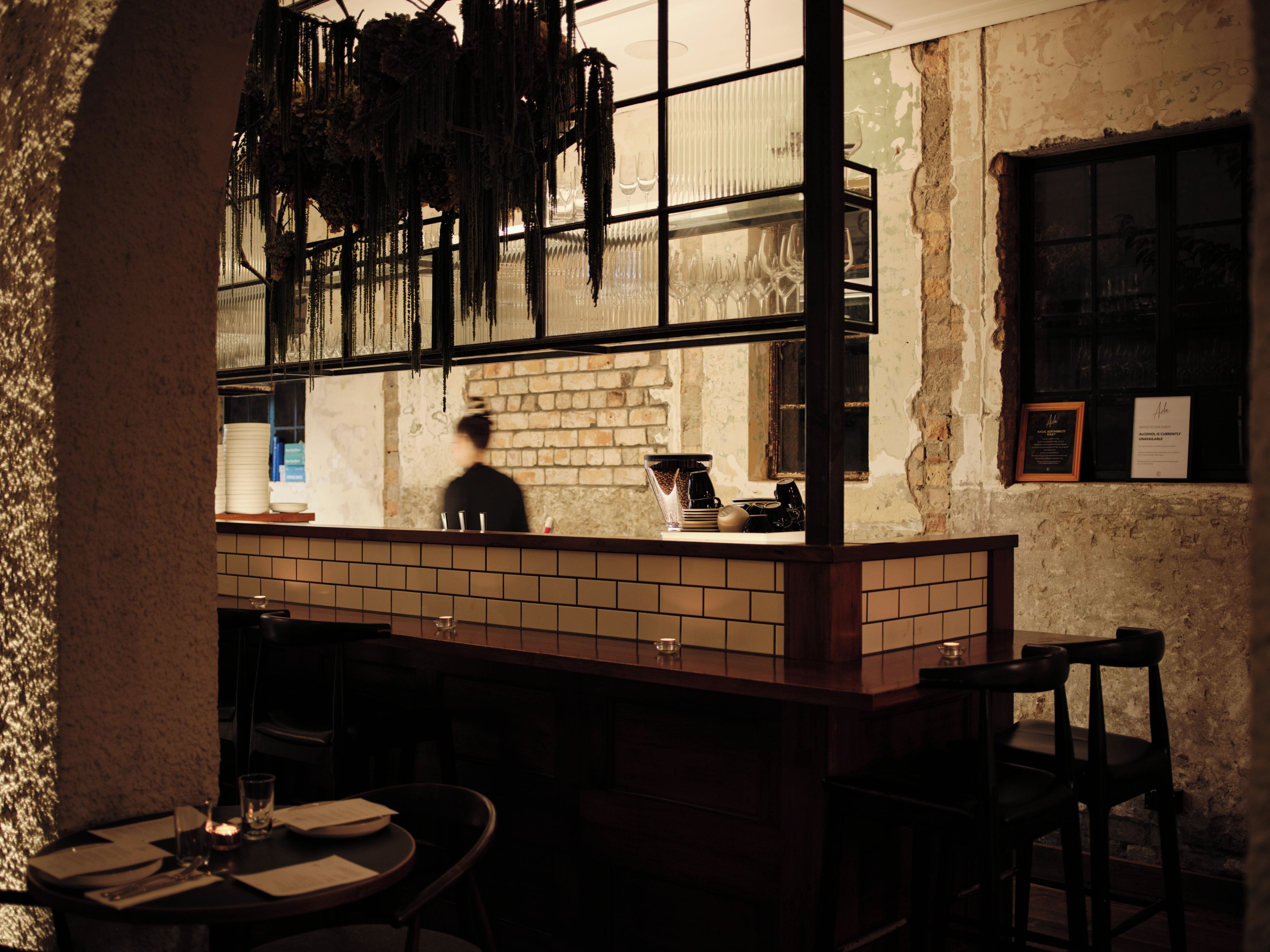 A bar area with a brick wall, hanging decorations, and a counter with various items.