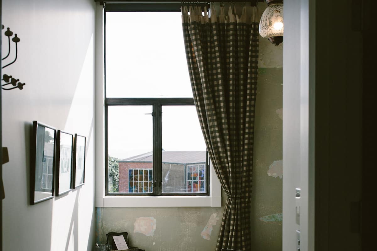 A small bedroom with a bed, a window with a view, a desk, and a chair.