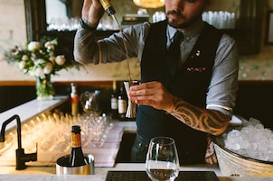 A bartender pouring a drink into a glass.