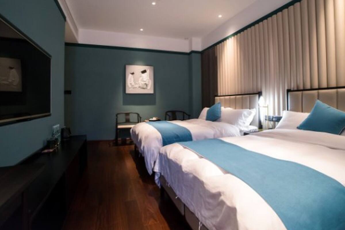 Habitación de hotel con dos camas, un escritorio y una silla.