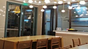 Un salón de conferencias con una larga mesa y sillas, una araña y una puerta de cristal que da a otra sala.