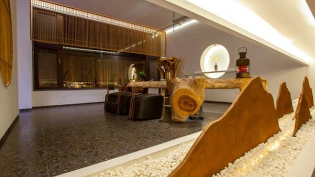 Un interior moderno con una zona de estar, una estructura decorativa de madera y un amplio ventanal con persianas.