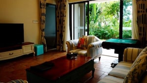 A living room with a sofa, a coffee table, a television, and a pool table. - Victoria Hotel Huizhou (Huizhou)