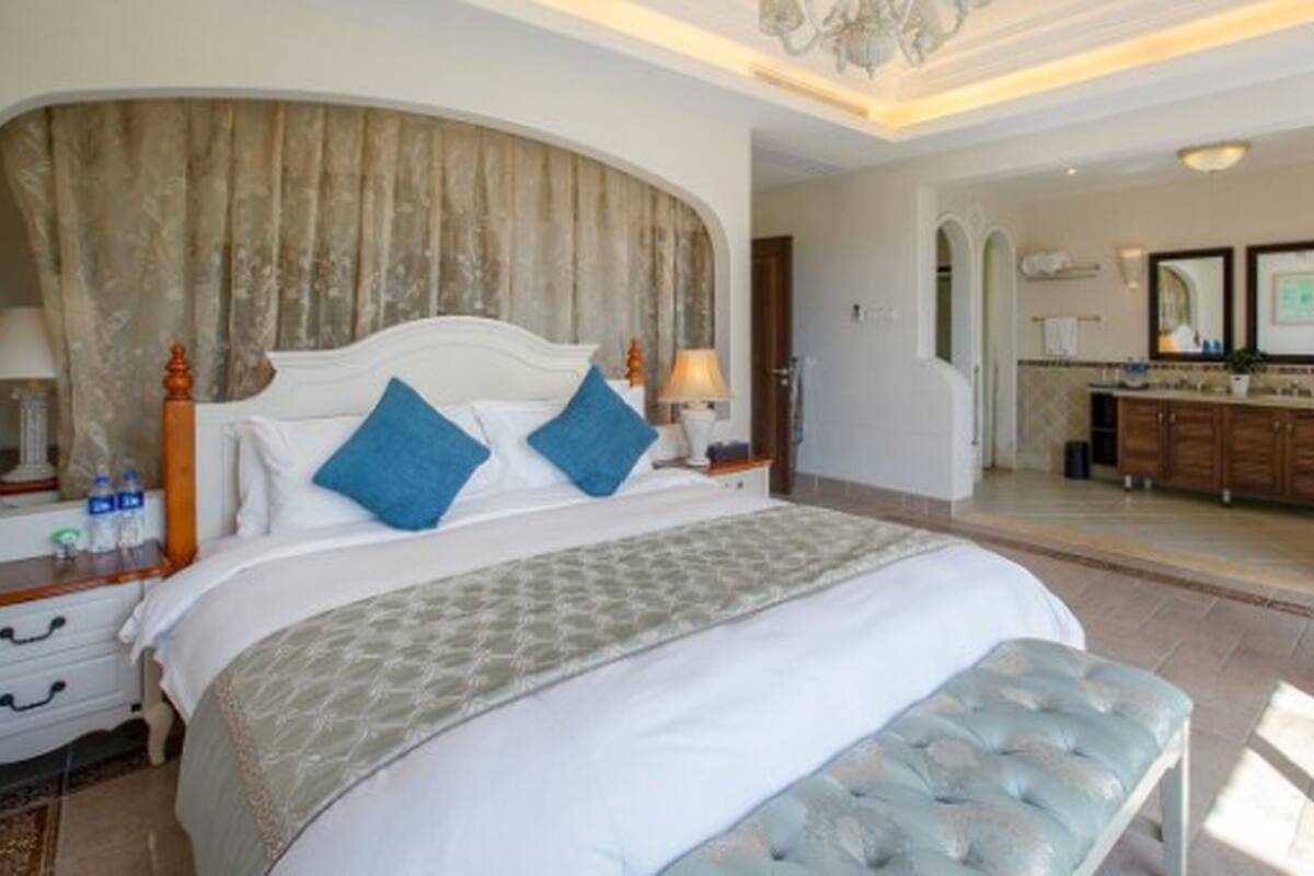 A spacious bedroom with a large bed, a sitting area, and a view of the bathroom.