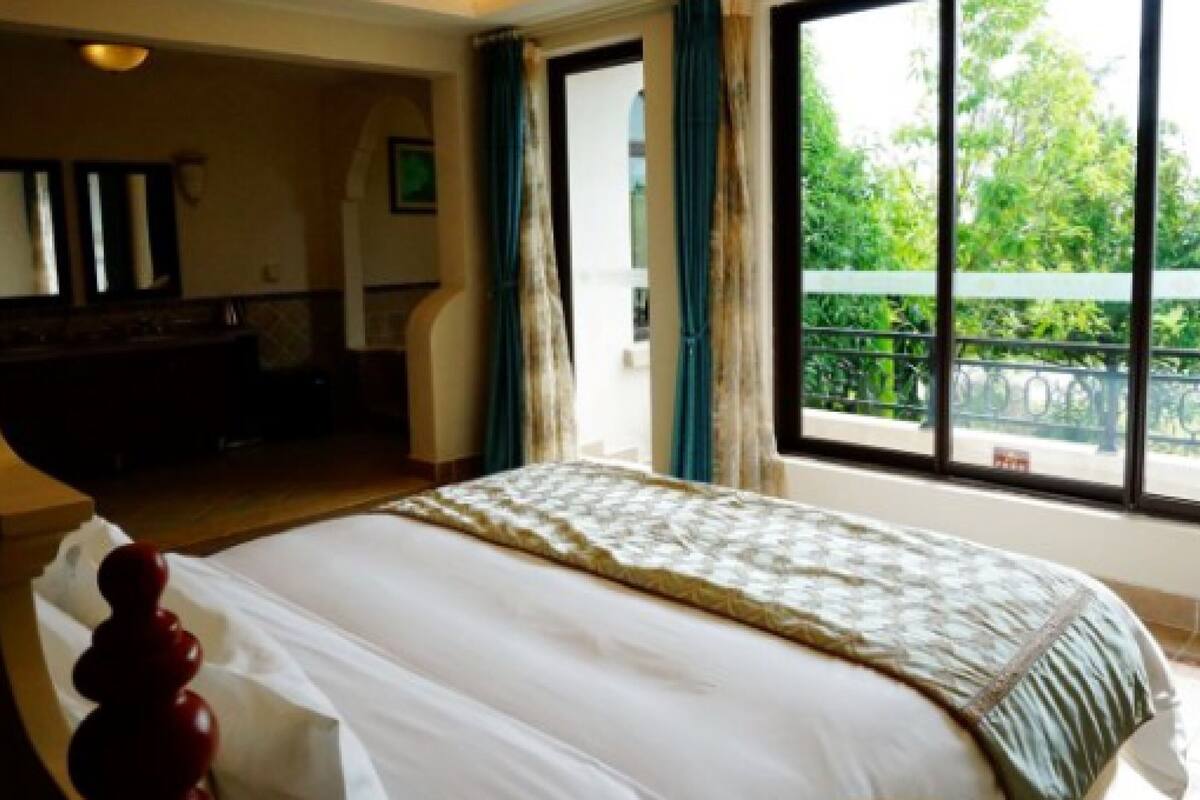 A bedroom with a large bed, a dresser, and a window with curtains.