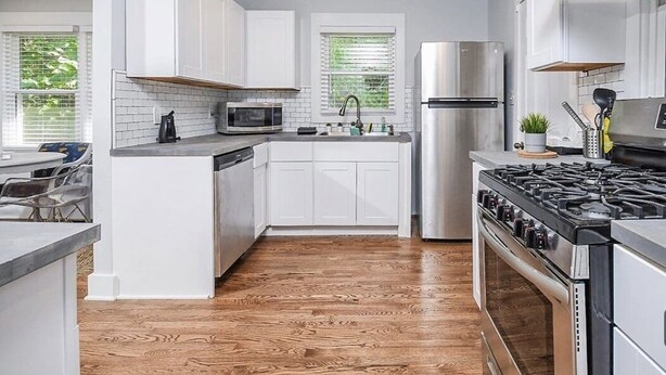 A modern kitchen with white cabinets, a stainless steel refrigerator, a microwave, a stove, and a sink. - Cool City Cottage (MINS FROM AIRPORT/CITY) 2B 1B (Stone Mountain)